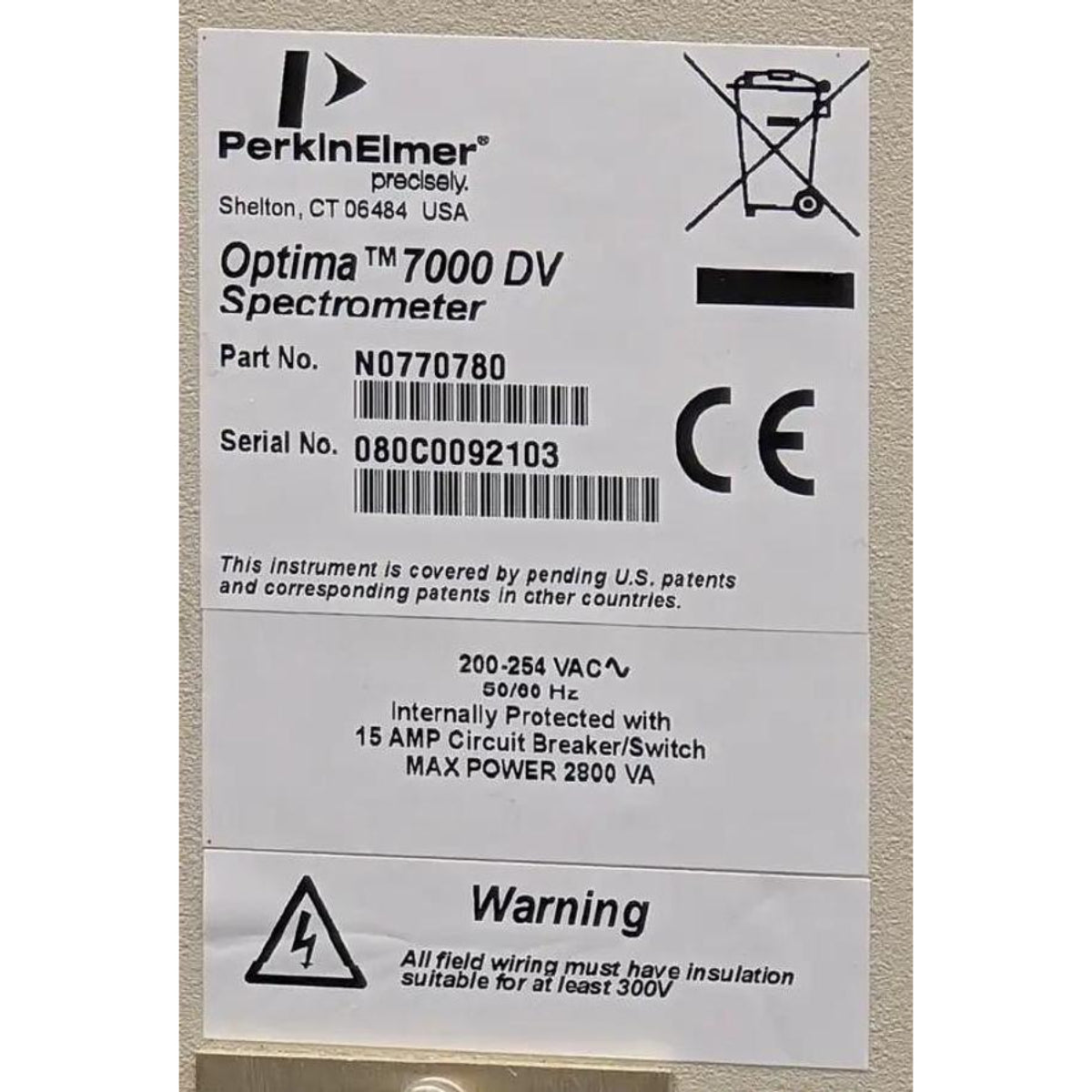 Close-up of the PerkinElmer Optima 7000 DV Spectrometer data plate showing Part No. N0770780, Serial No. 080C0092103, CE mark, electrical specifications of 200-254 VAC 50/60 Hz with 15 AMP circuit breaker and 2800 VA max power, manufactured by PerkinElmer in Shelton CT 06484 USA