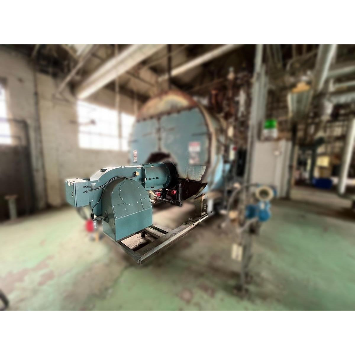 Cleaver Brooks 700HP industrial natural gas burner assembly skid-mounted and installed on Burnham 700HP three-pass steam boiler in industrial facility prior to removal