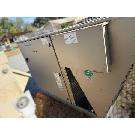 Daikin DPS012AHHE2DW-4 packaged rooftop HVAC unit side view showing condenser coil section, R-410A non-flammable gas label, access panels, and beige powder-coated cabinet