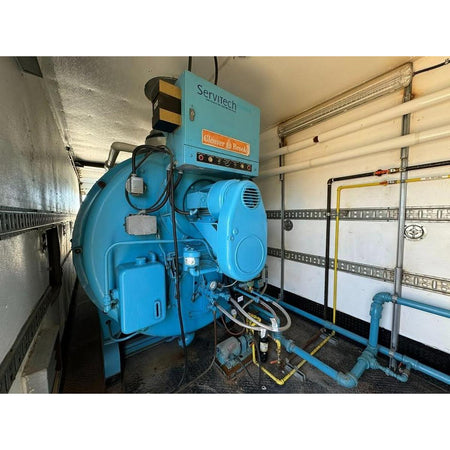 Blue industrial machine with 'Servitech' branding in a mechanical room.