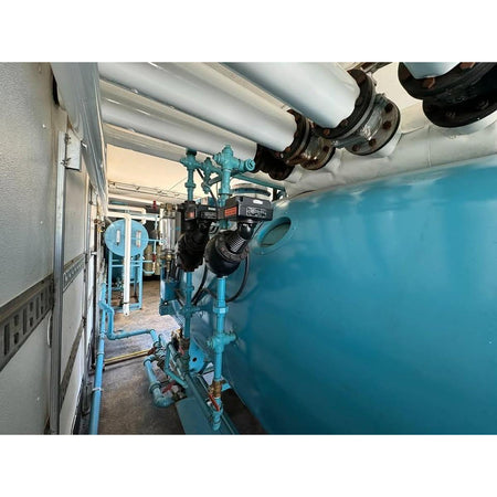 Industrial setting with blue machinery and pipes in a mechanical room.