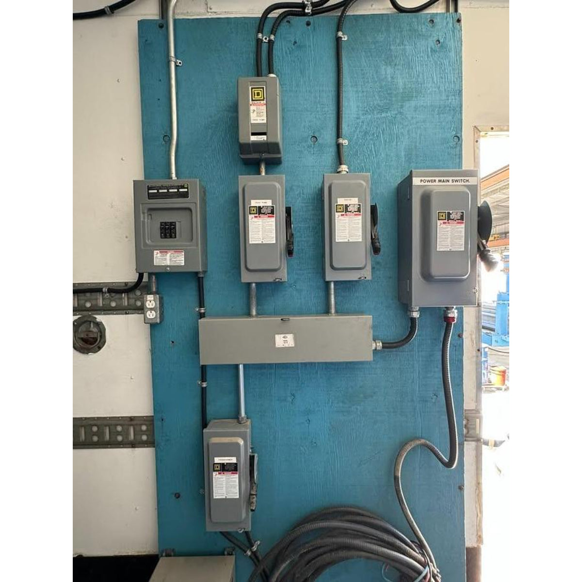 Electrical panel with multiple switches and wiring on a blue wall.