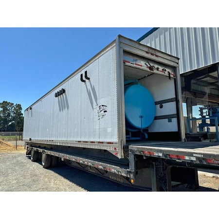 Trailer with open cargo area revealing a large blue tank against a clear blue sky.