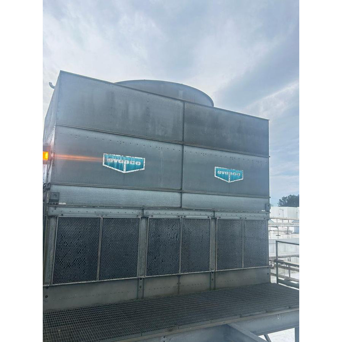 Large industrial cooling tower with Evapco branding against a cloudy sky.