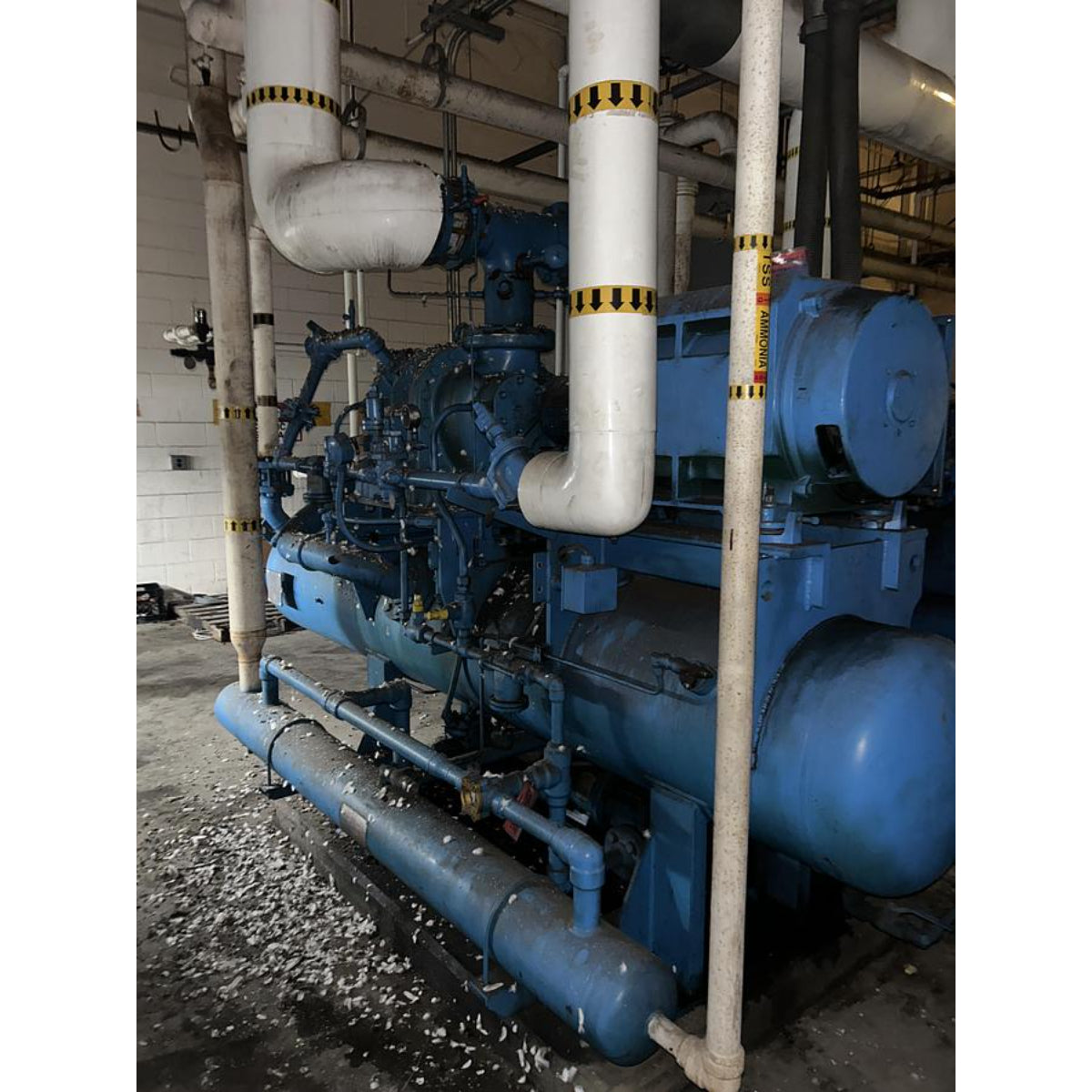 Large blue industrial machine with pipes in a mechanical room
