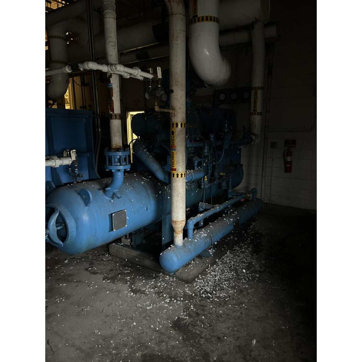 Industrial machinery with blue components and pipes in a dimly lit room