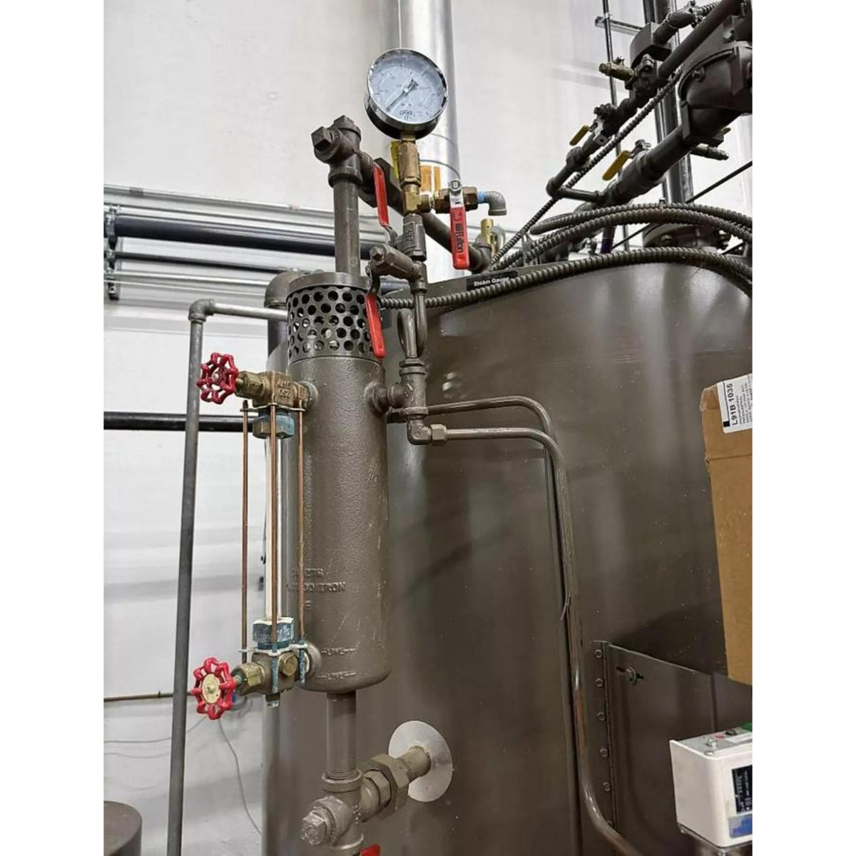 Industrial boiler with various pipes and valves in a mechanical room.