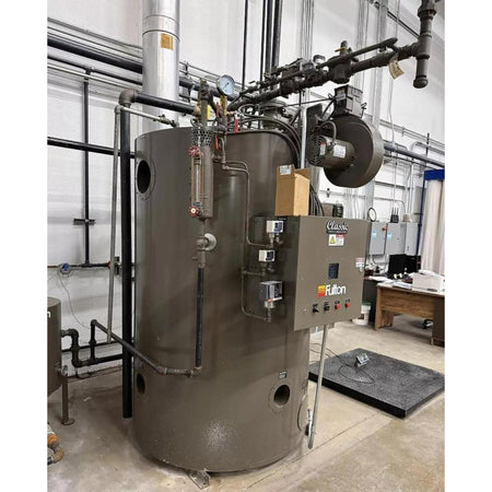 Large industrial boiler with various pipes and equipment in a room with large windows.