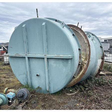 Large metal cylindrical tanks outdoors under a cloudy sky