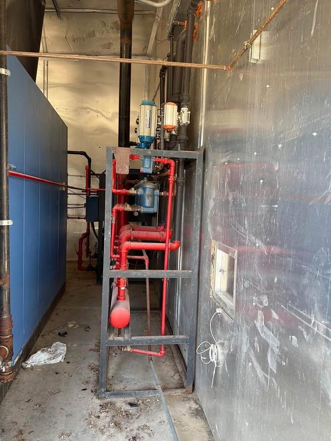 Industrial setting with blue walls, red pipes, and metallic equipment.