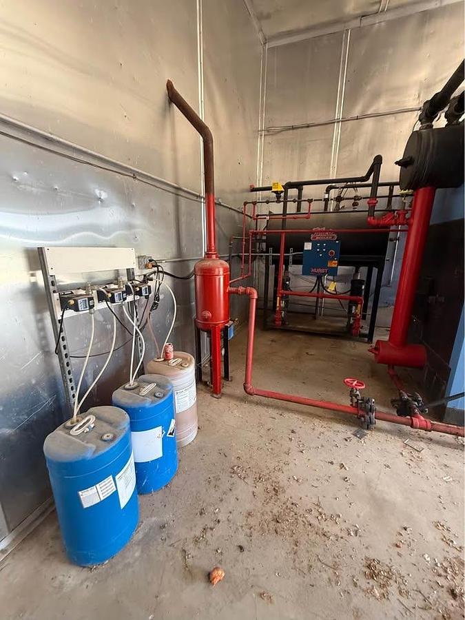 Industrial setting with blue barrels, red pipes, and equipment in a warehouse.