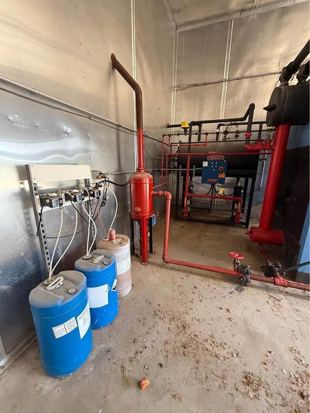 Industrial setting with blue barrels, red pipes, and equipment in a warehouse.