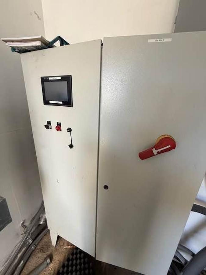 Metal control panel with a screen and red handle on a white background
