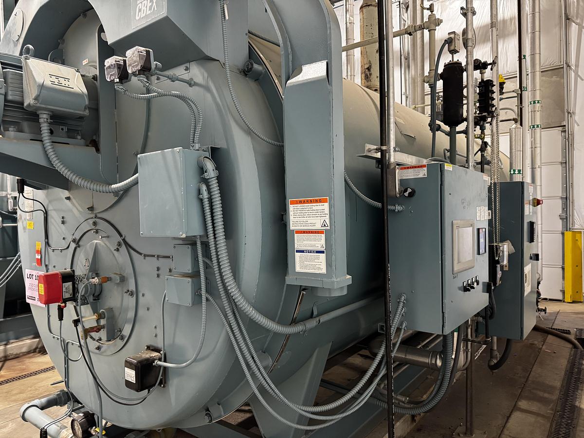 Large industrial machine with various components and labels in a workshop setting