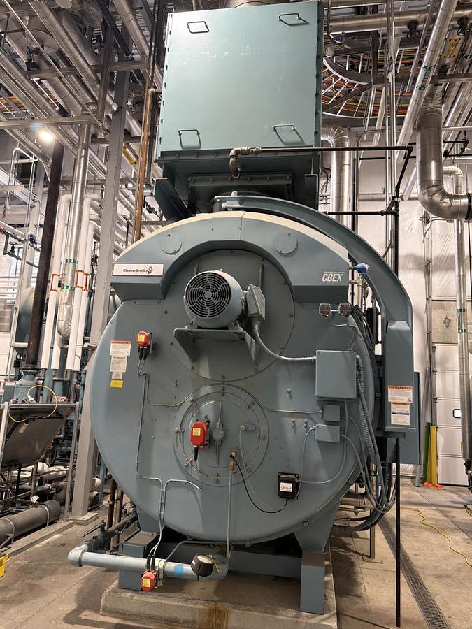 Large industrial boiler in a factory setting with pipes and machinery.